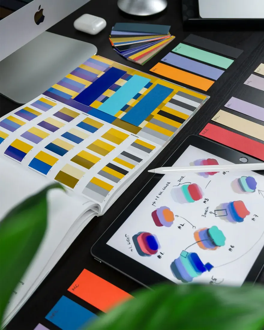 Colour swatches, a Pantone book and design sketches on a studio desk